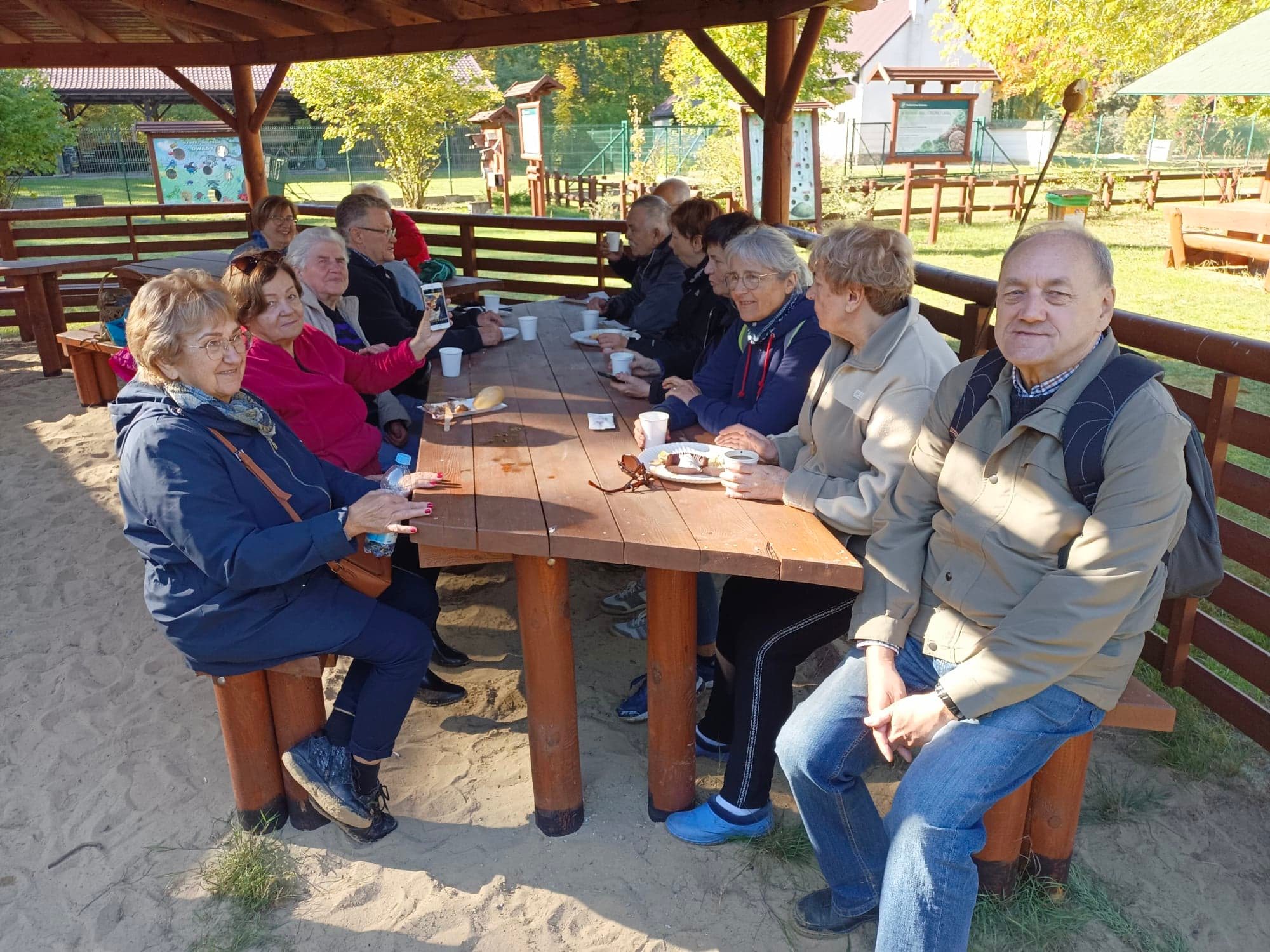 Na zdjęciu przedstawieni są studenci UTW, którzy rozmawiają i spożywają posiłek.