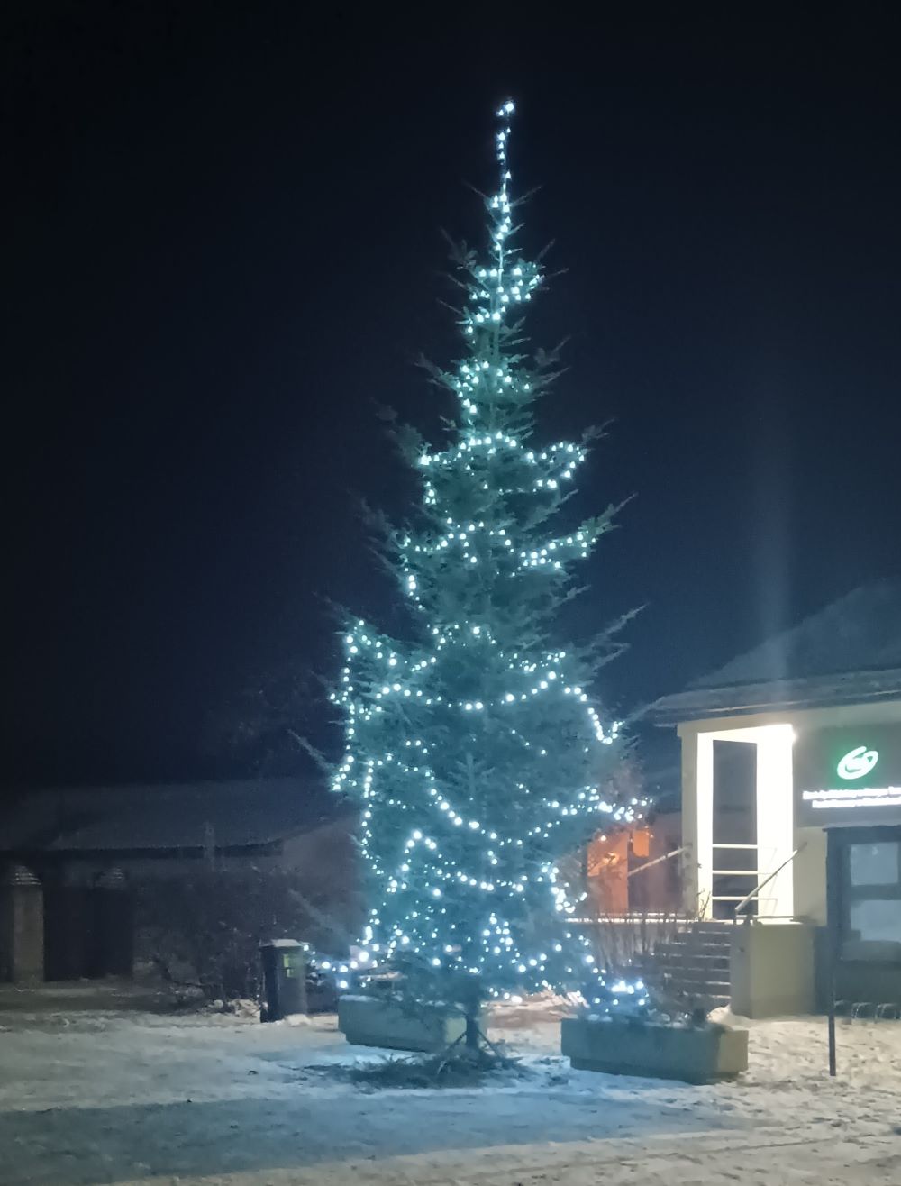 Choinka dekoracyjna zielona, oświetlona białymi zimnymi światełkami.