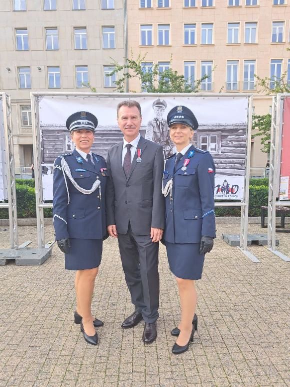 Na pierwszym planie stoją trzy osoby. Dwie kobiety i&nbsp;jeden mężczyzna, na&nbsp;tle baneru w&nbsp;kolorze biało-czarnego.