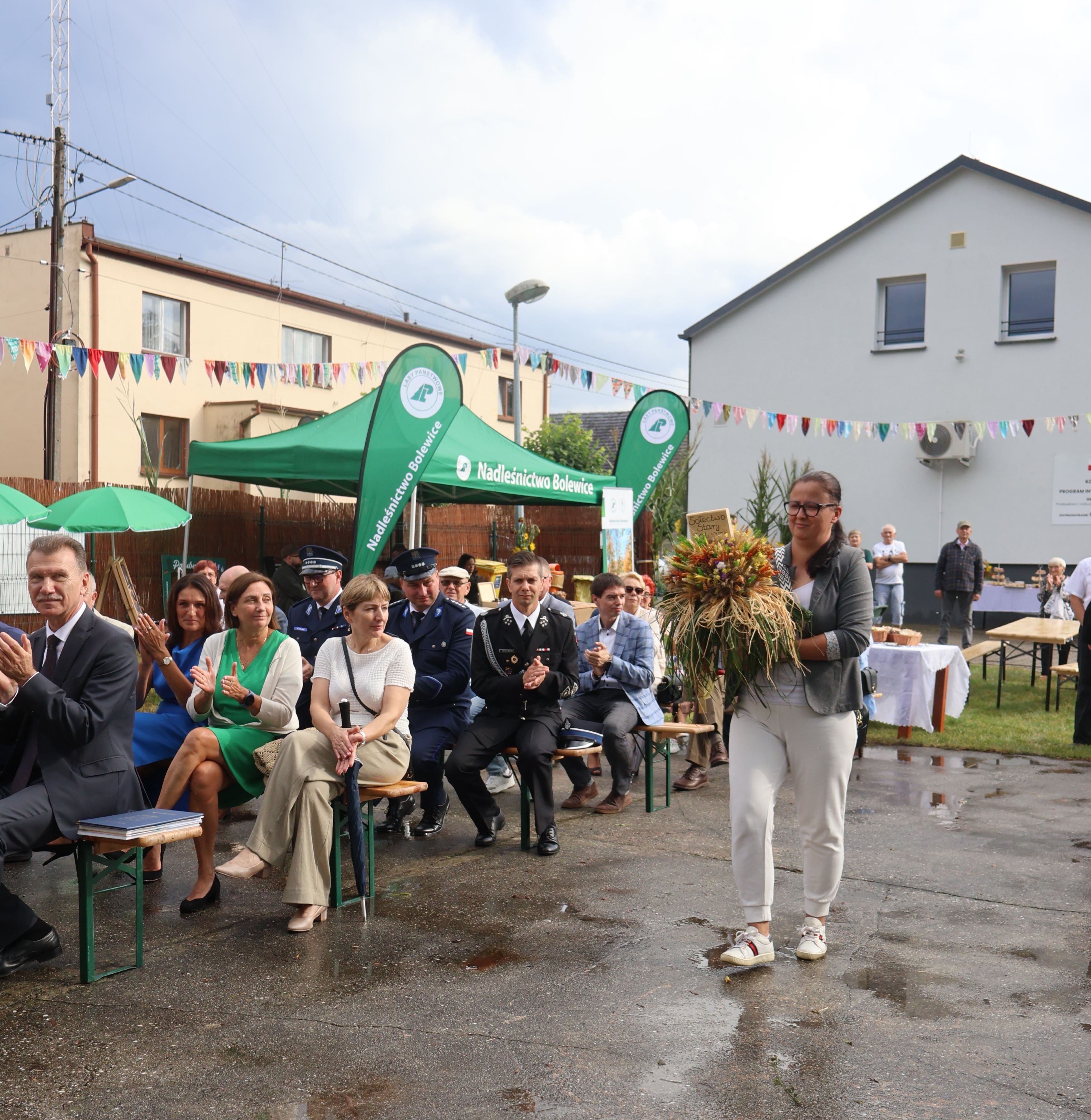 Odczytywanie opisu sołectwa Stary Folwark. Na zdjęciu jest pokazany sołtys Sołectwa Stary Folwark, kt&oacute;ry niesie bukiet dożynkowy. 