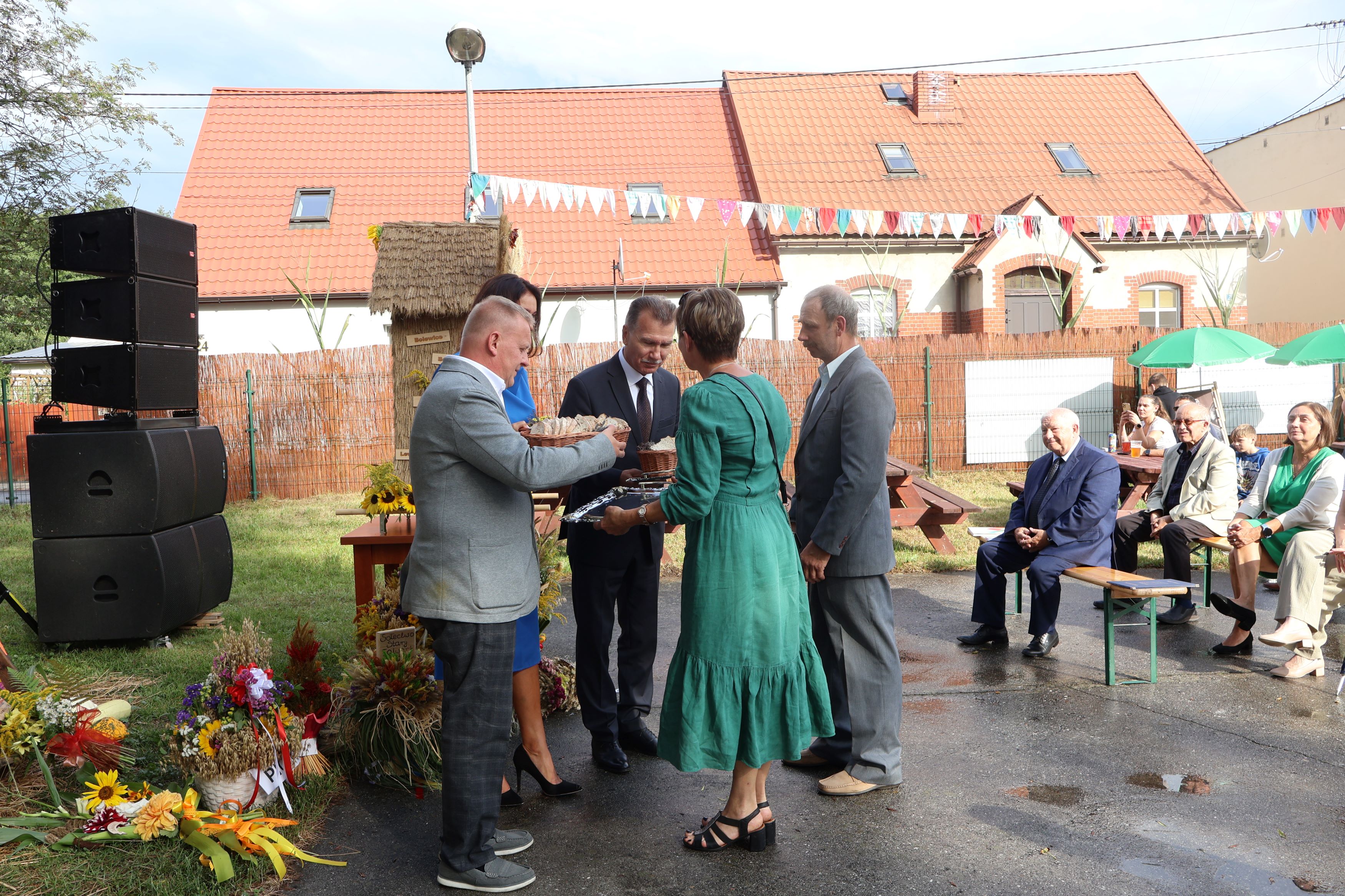 Przekazywanie chleba przez starost&oacute;w dożynek na&nbsp;ręce władz samorządowych, przed sceną. 